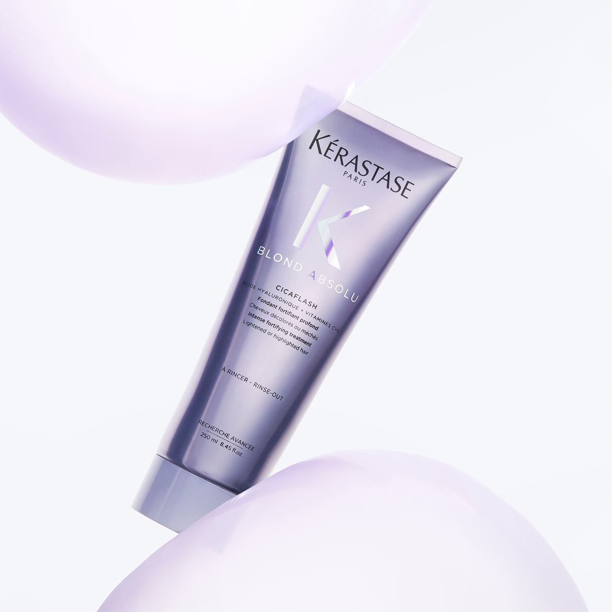 Trattamento Kérastase Blond Absolu Cicaflash in tubo lilla fluttuante tra sfere trasparenti viola