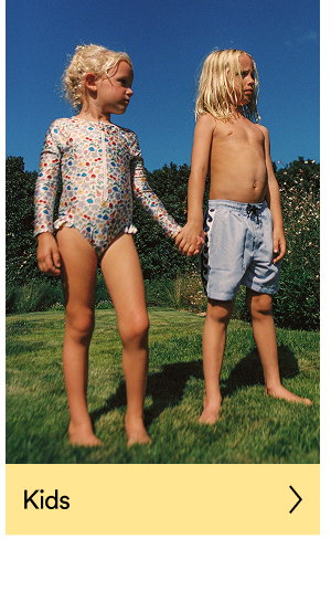 Two children holding hands in grass wearing Cotton On kids clothing
