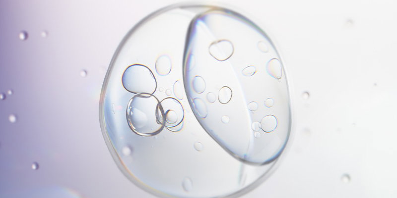 Close-up of clear serum droplets suspended within a liquid sphere, illustrating advanced skincare formulation and ingredient delivery.