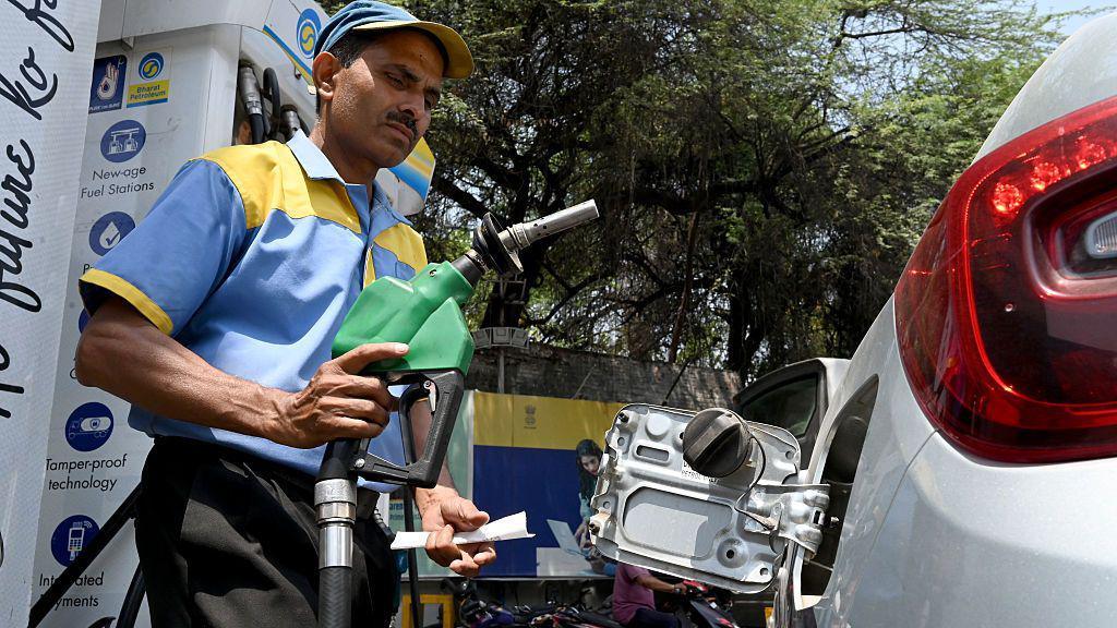 A petrol pump attendant fills fuel in a vehicle at a petrol station in India.