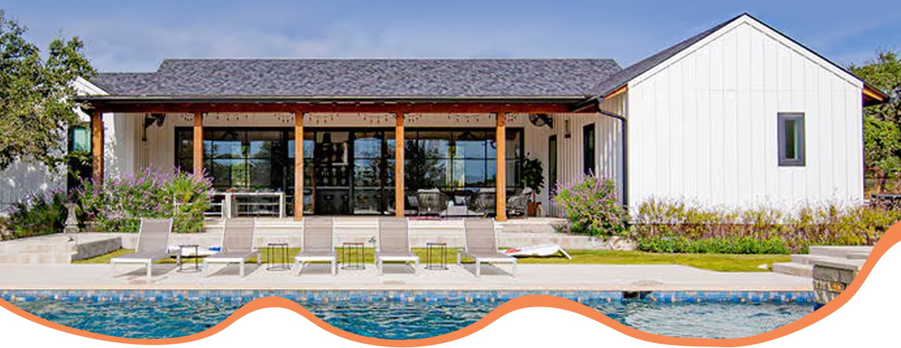 Pool in front of a single-story home with a covered patio, glass windows, and lounge chairs.