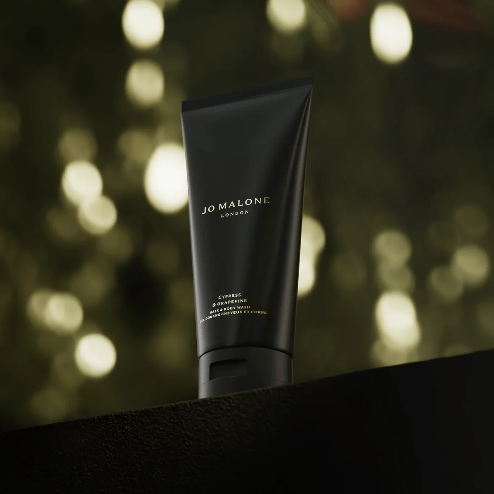 Cypress & Grapevine Hair & Body Wash against a softly blurred, warm bokeh background.