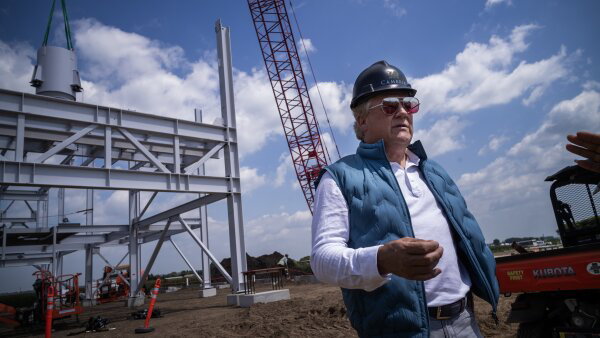 Cambria CEO Marty Davis wearing a long-sleeve white shirt underneath an open puffier vest. He also has on a hard hat and shades. 