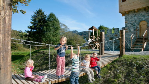 Spielplatz mit Hängebrücke und spielenden Kindern