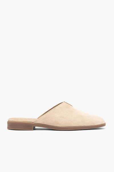 Beige suede slip-on mule with flat wooden heel, side view on white background