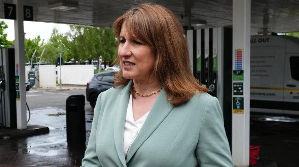 Rachel Reeves speaks to reporters on a petrol station forecourt. She wears a green jacket and white top and has medium length brown hair.
