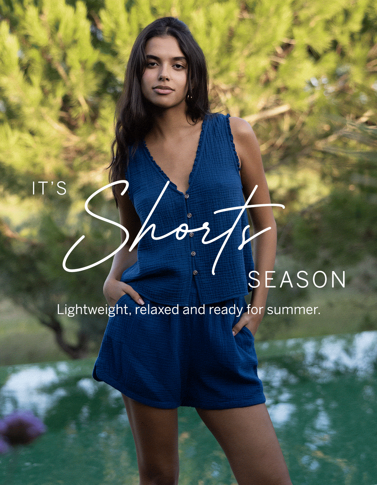 Model wearing a lightweight blue sleeveless top and matching shorts outdoors, with overlay text promoting relaxed summer style.