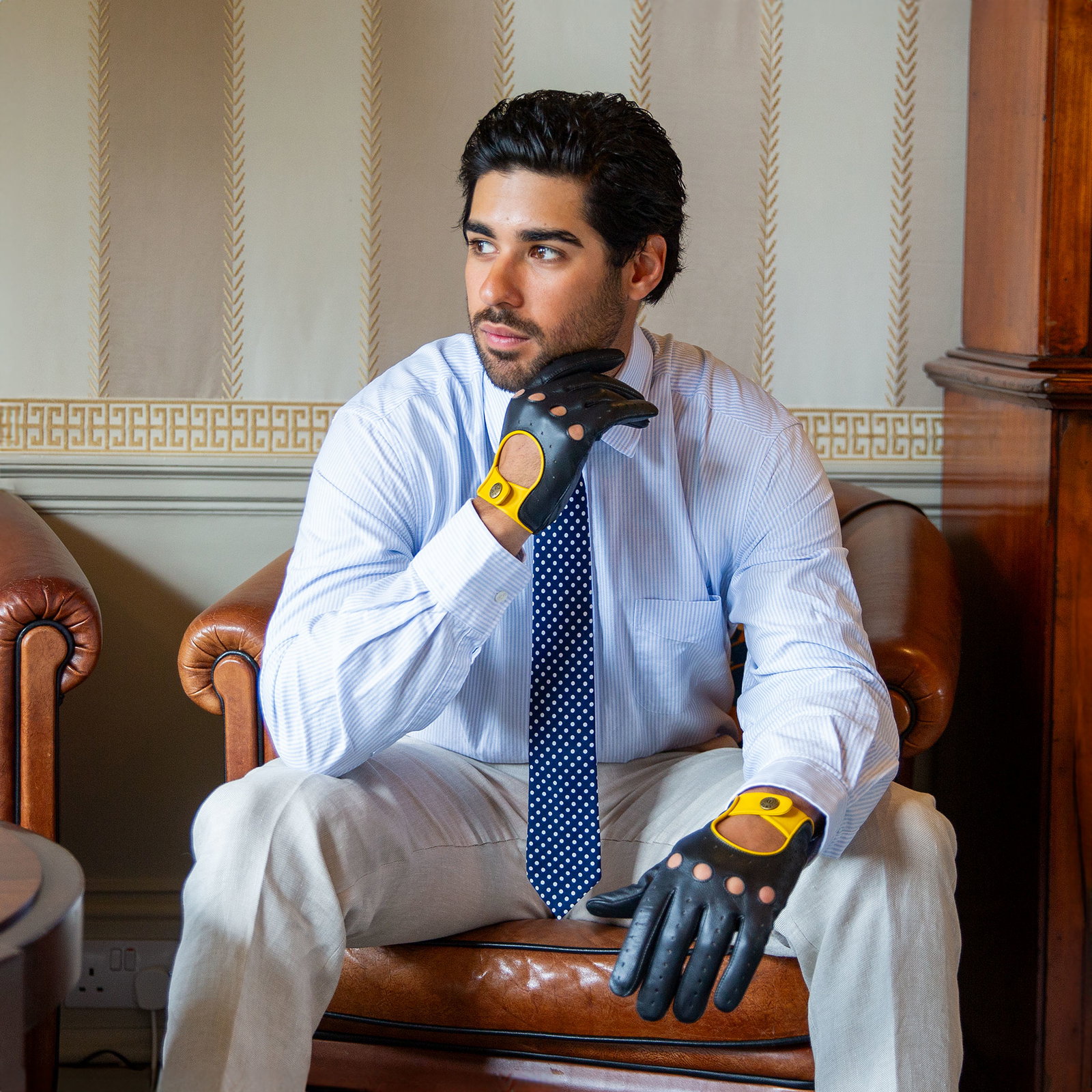 Man wearing touchscreen three-colour leather driving gloves in black and yellow.