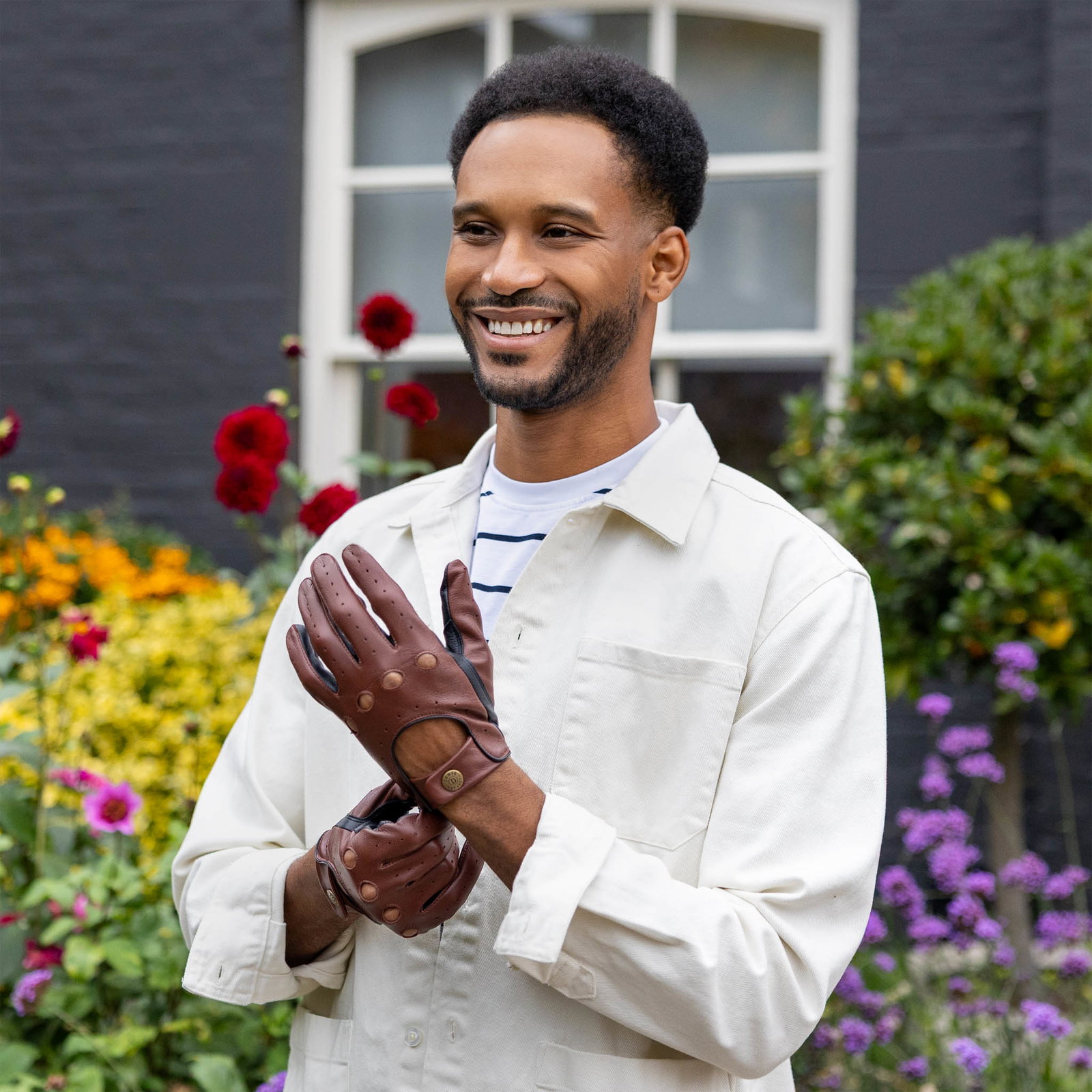 Man wearing touchscreen leather gloves in brown and black in the garden. 