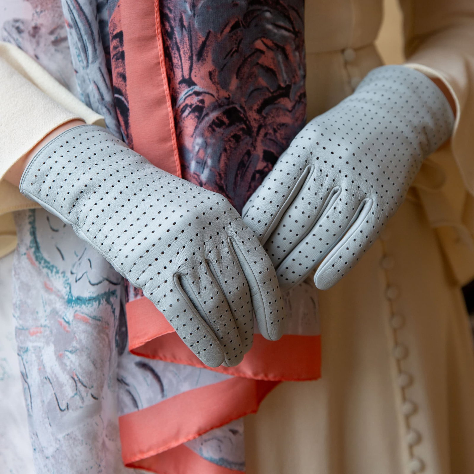 Close up of woman wearing perforated leather gloves in silver.