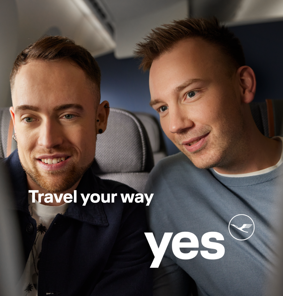 Two passengers seated on an airplane looking at a screen together.