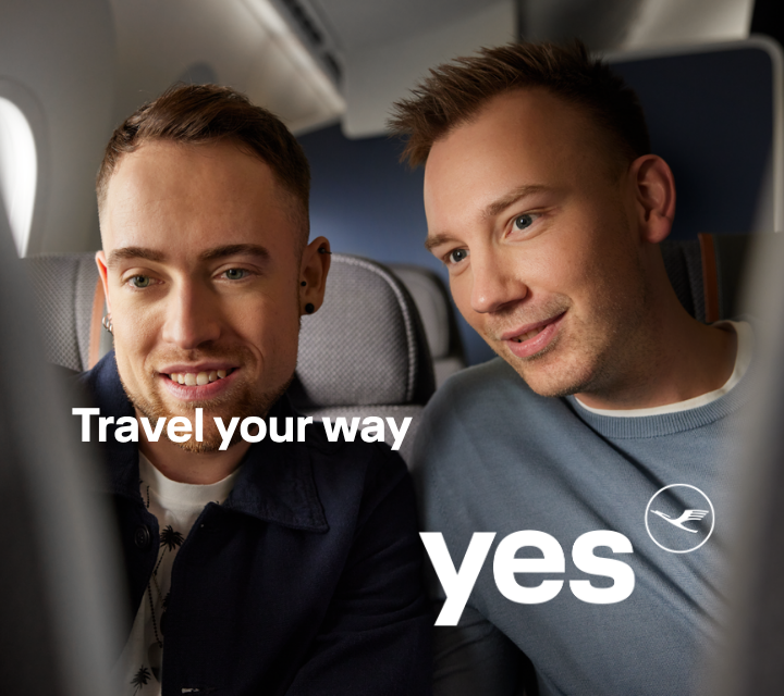 Two passengers seated on an airplane looking at a screen together.