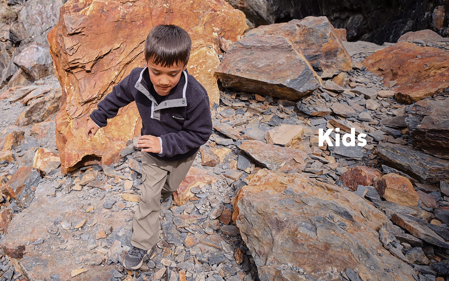 Young boy climbing up rocks. Kids.
