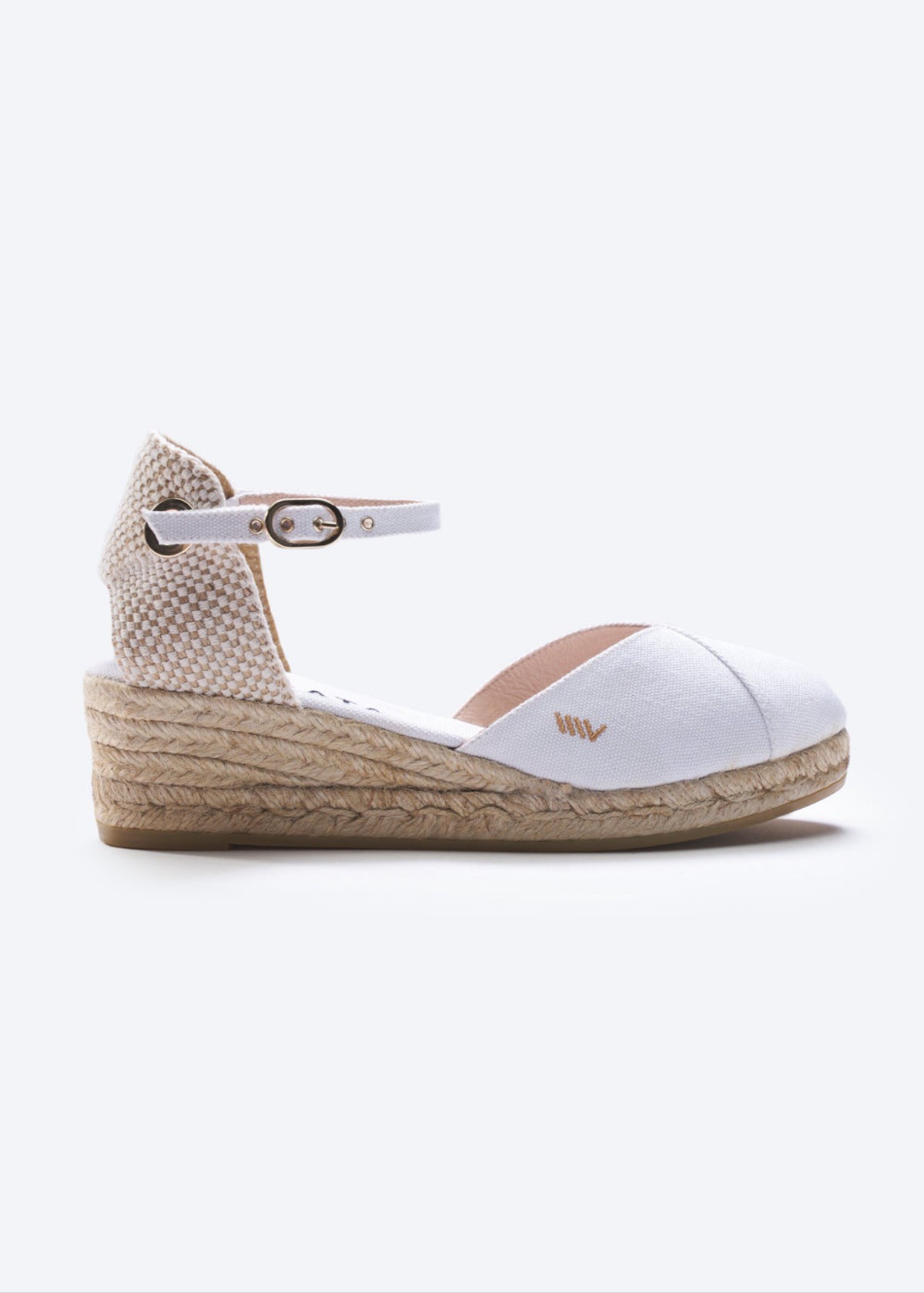 White canvas espadrille wedge sandals with ankle strap and braided jute heel on a clean background.