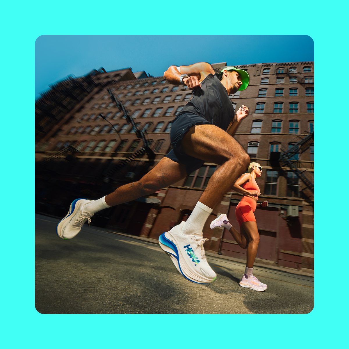 An image of two people running on a street with a building and blue skies in the background.
