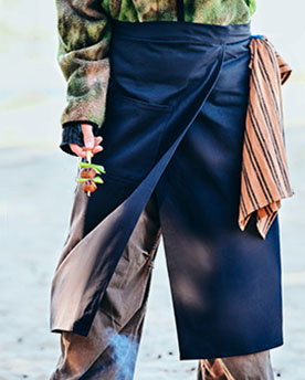 A campground cook wearing the SOLUPPGÅNG waist apron.
