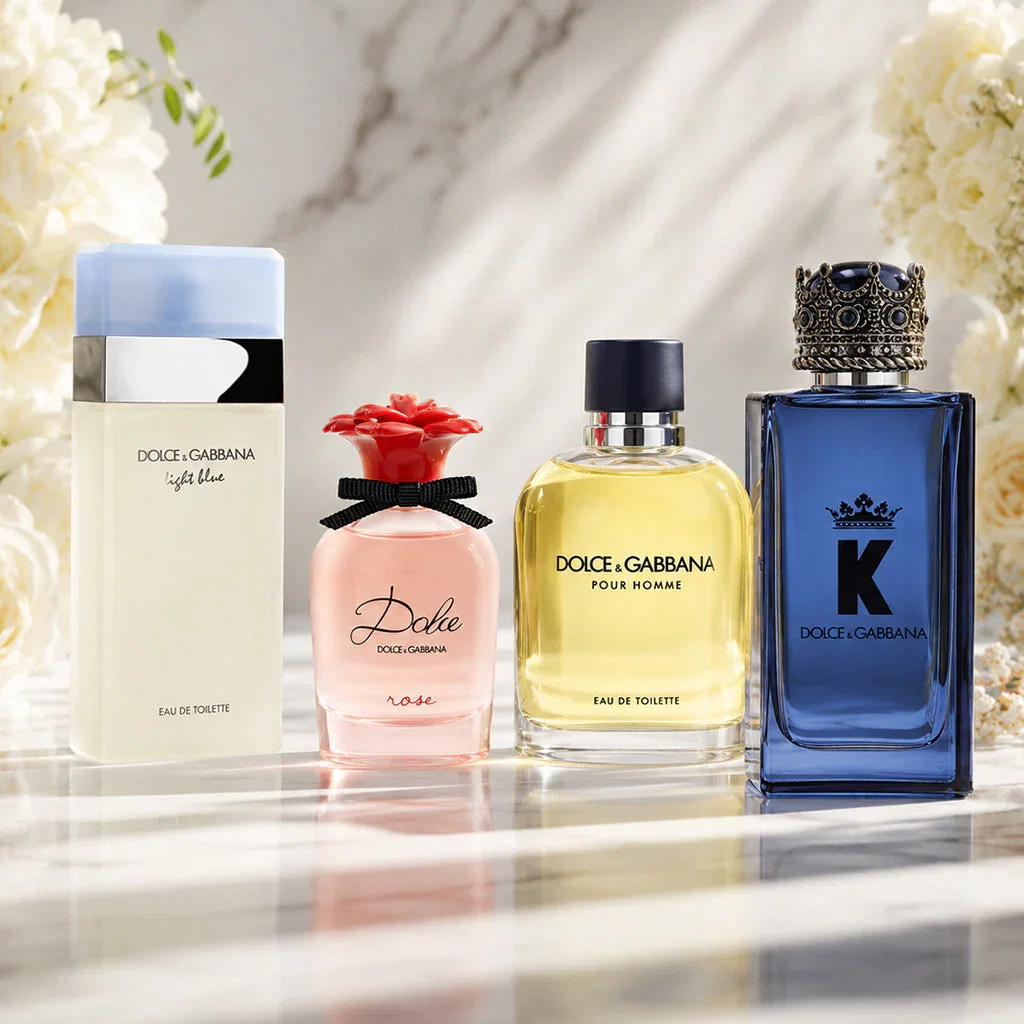 Dolce & Gabbana fragrance collection featuring Light Blue, Dolce Rose, Pour Homme, and K perfumes displayed on marble surface with white flowers.