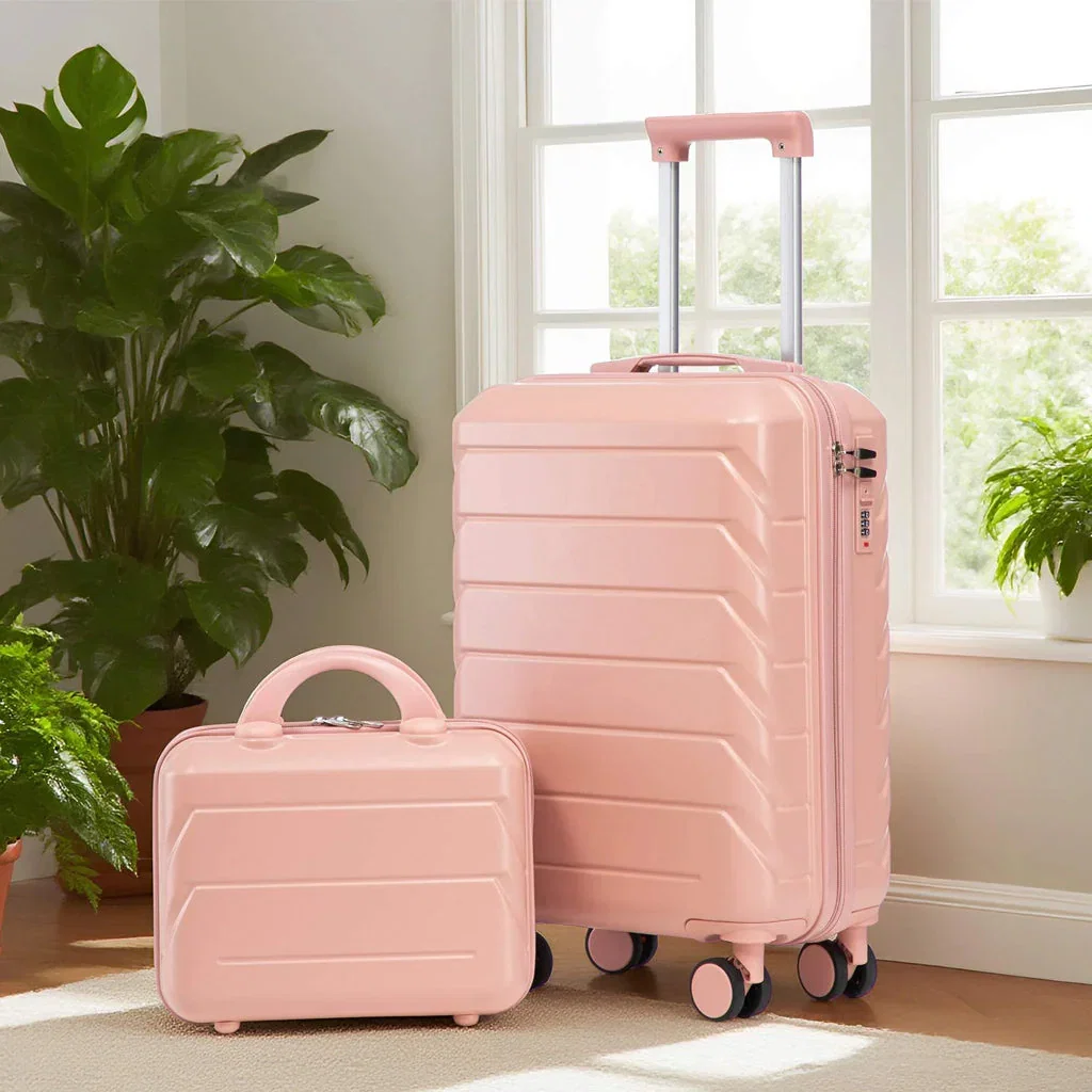 A pink luggage set with a large rolling suitcase and small carry-on case displayed in a bright room with plants and windows.