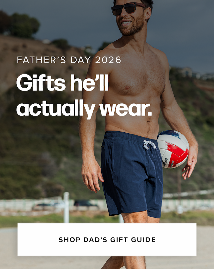 A shirtless man in sunglasses and navy blue shorts walks on a beach while holding a red, white, and blue volleyball. Text reads: 'Father’s Day 2026 Gifts he’ll actually wear. Shop Dad’s Gift Guide'