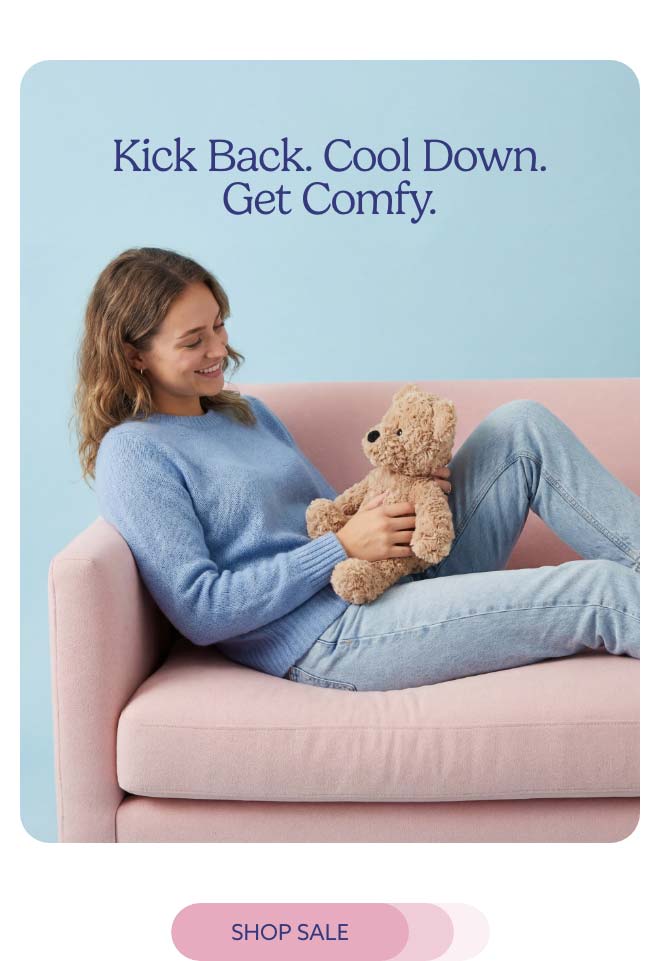 A woman relaxing on a couch with Brown Curly Bear Warmies. Shop Sale.