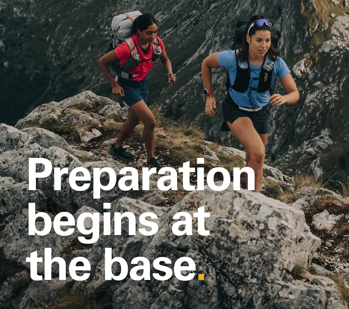 'Preparation begins at the base' Text over the image of two women hiking in the hills wearing Rab first layers.