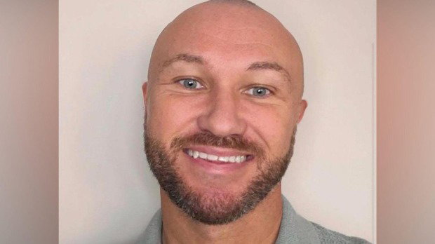 Chris Kennedy - a bald man with blue eyes and a brown beard - smiles at the camera in front of a plain background.