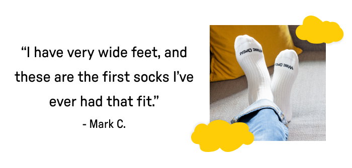 Man's feet in white socks with black lettering "I have very wide feet, and these are the first socks I've ever had that fit."
