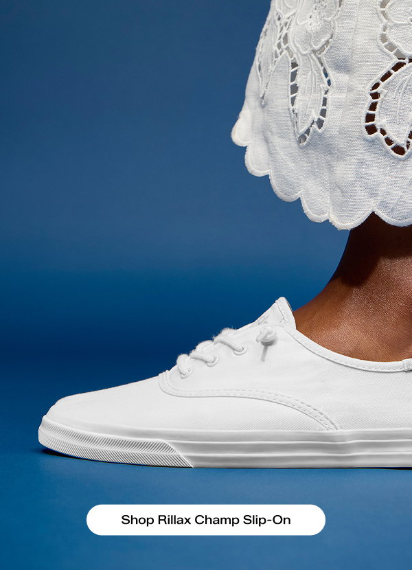 A close-up view of the Rillax Champ Soft Leather Slip-On in white, paired with a scalloped-edge white linen skirt. Shop Rillax Champ Slip-On.