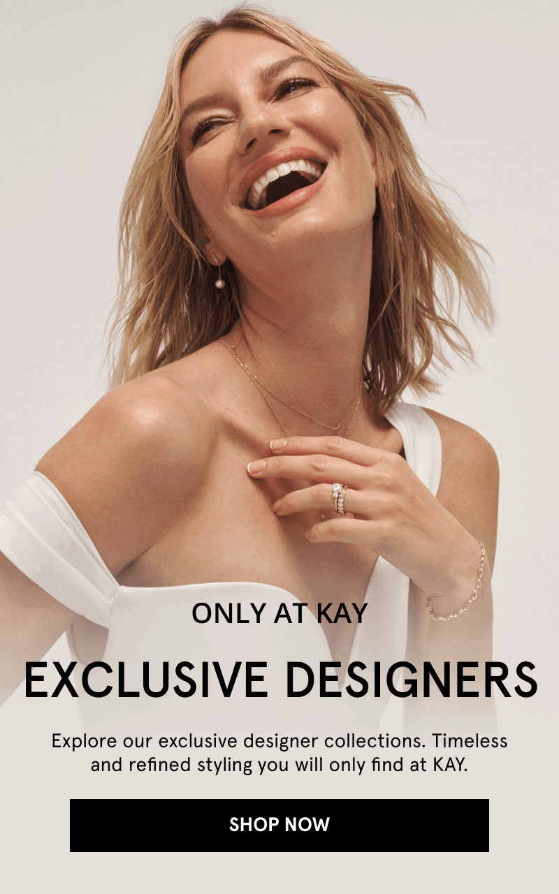 Woman wearing pearl drop earrings, delicate chains, and diamond rings. Only at KAY. Exclusive designers. Click shop now.