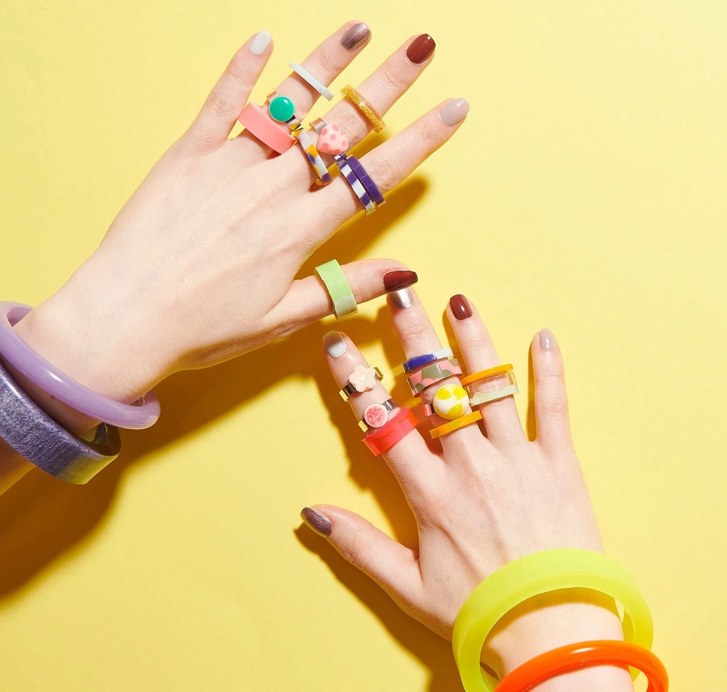 Hände mit bunten Ringen und Armbändern aus Resin