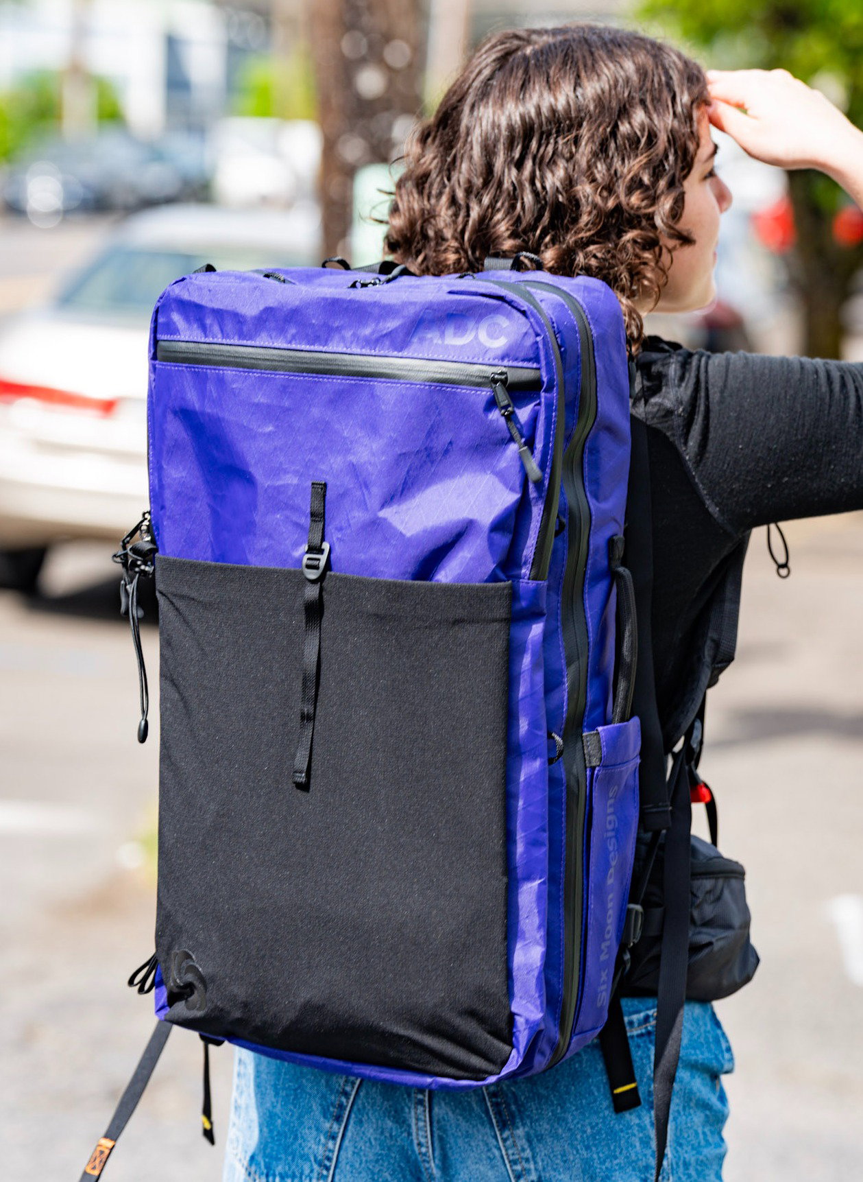 girl with purple travel backpack looking into sun