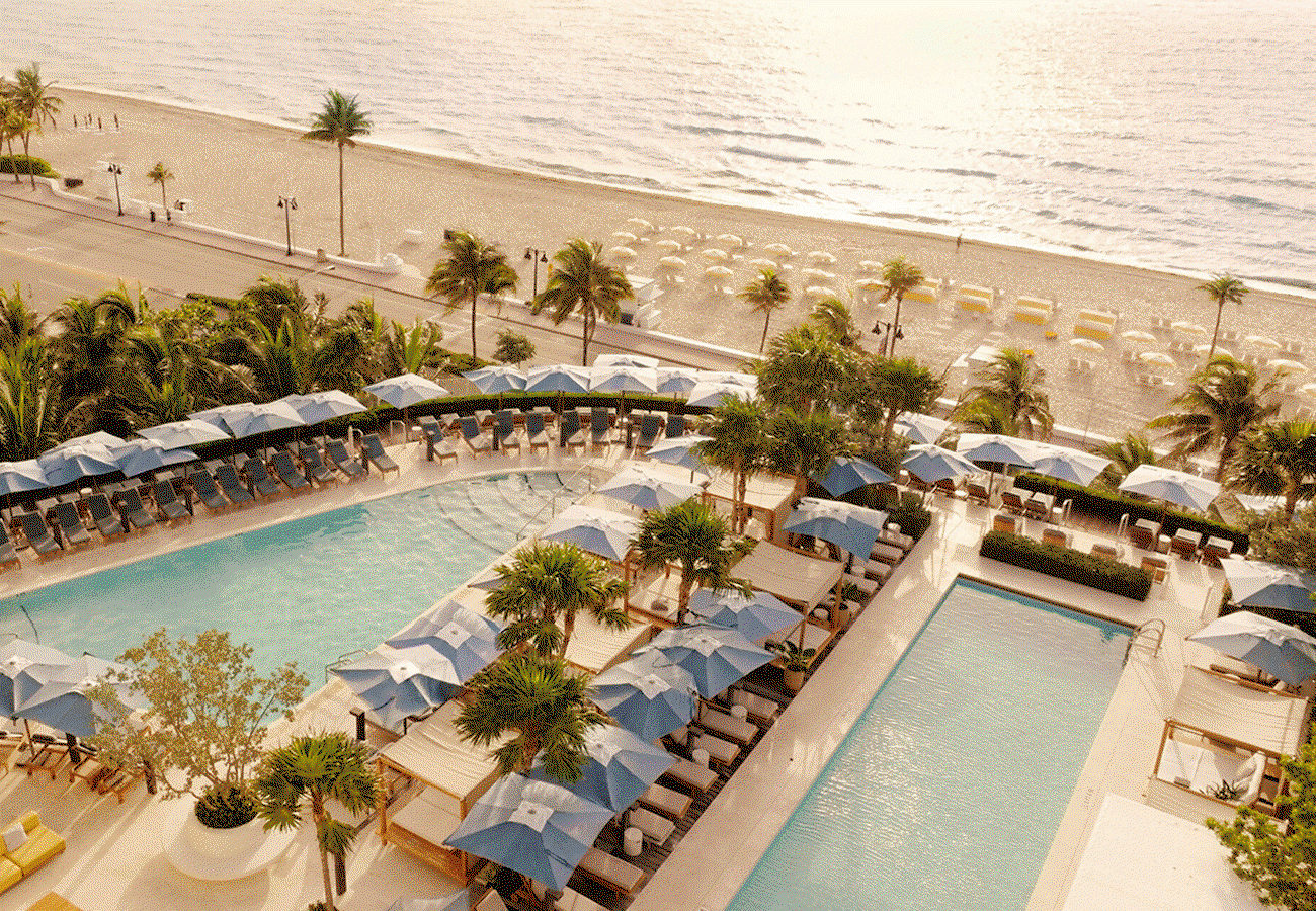 Hero GIF featuring 3 frames: 1) Two pools surrounded by chaise loungers and umbrellas, looking out to the beach. 2) An overhead shot of a man walking along the beach between yellow and white umbrellas. 3) A woman on a bike stands with her bike along a palm tree pathway.