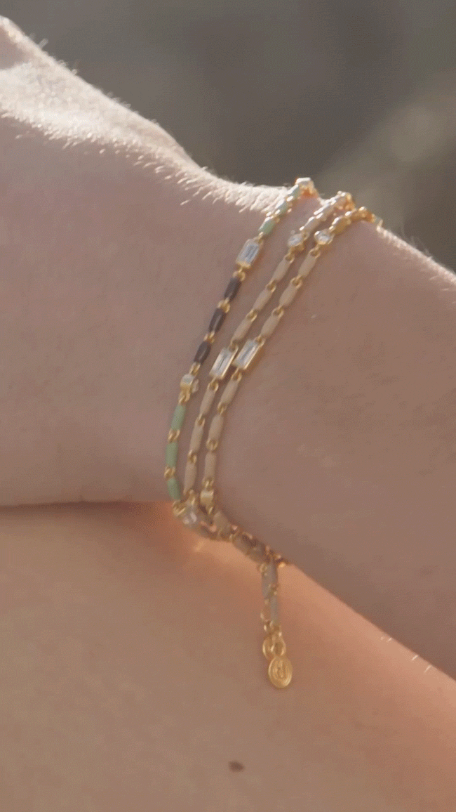 GIF of model wearing Terre Enamel layered on her wrist at the beach.