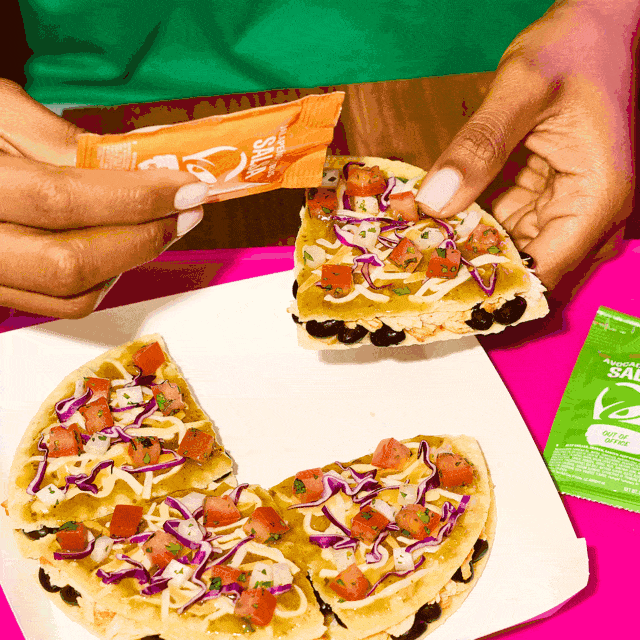 A hand holding a slice of Cantina Chicken Mexican Pizza with the other three slices on a plate.