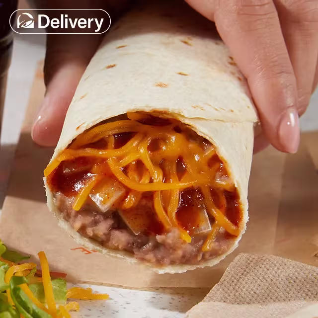 A hand holding a Taco Bell Bean Burrito.