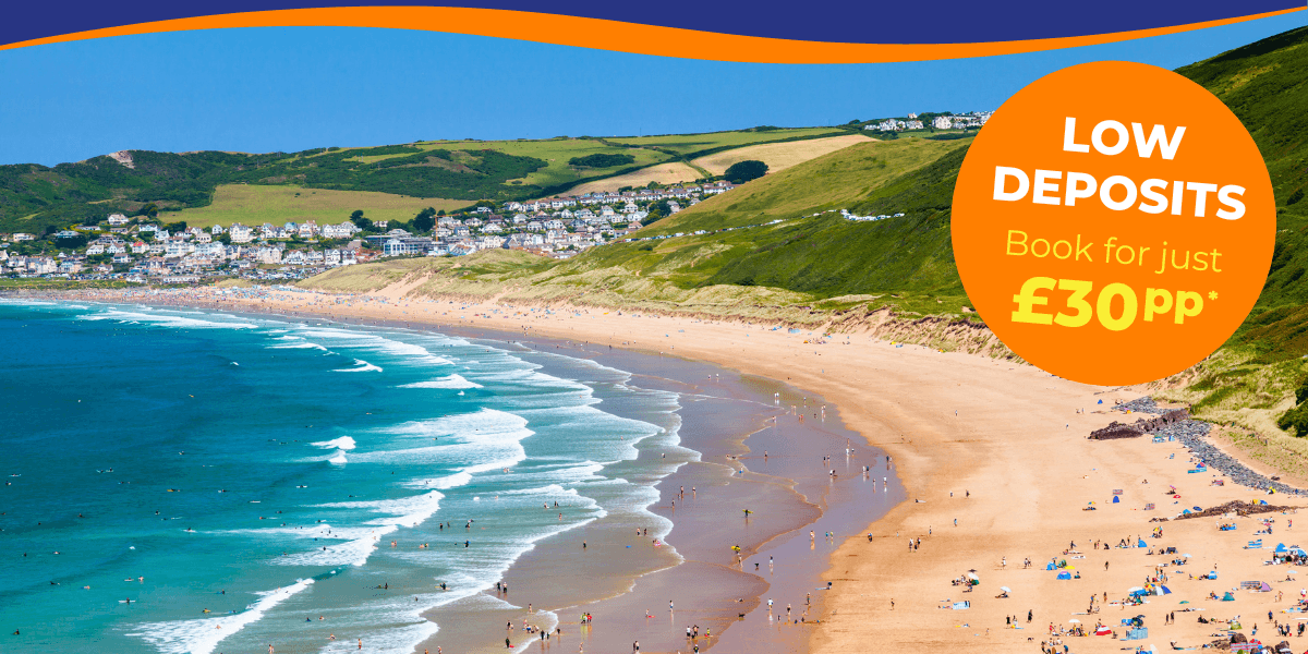 A scenic beach view with people enjoying the sun, waves, and hills in the background.