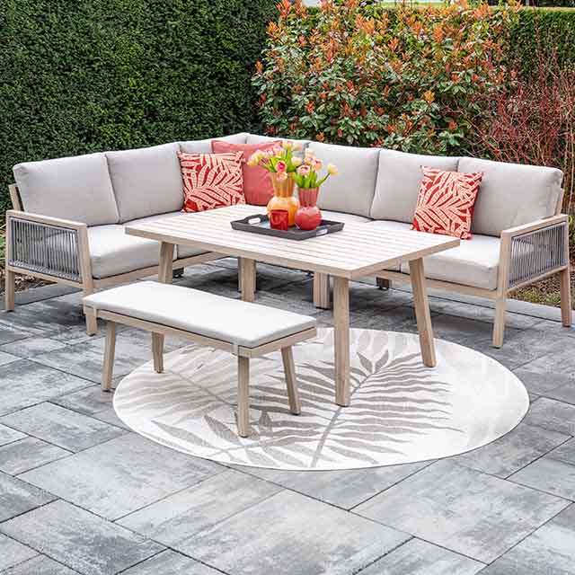 Outdoor patio set with a wooden table, bench, and cushioned seating. Decor includes red-patterned pillows and a vase with flowers.