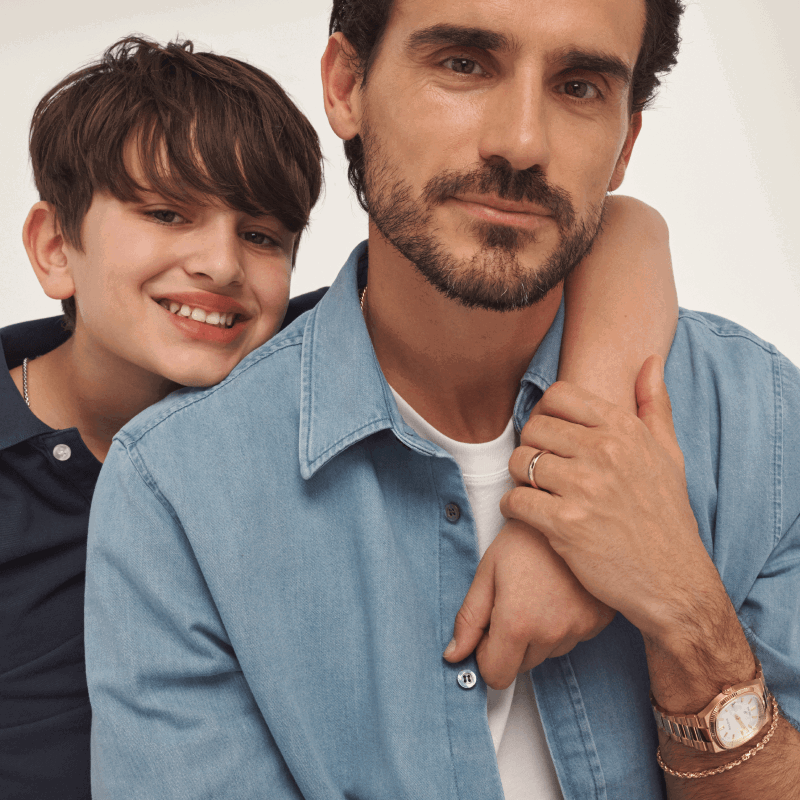 Father and son embracing. Father wearing gold watch and gold bracelet.