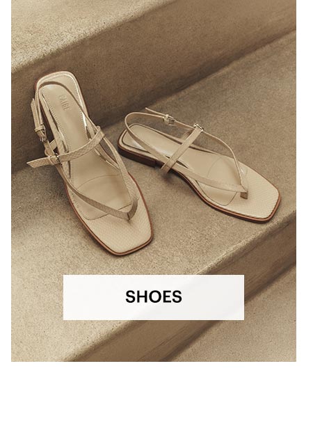 Pair of cream leather thong flat sandals artfully placed on a stone staircase. Shop women's shoes.
