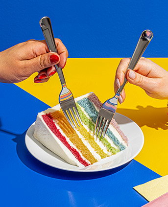 Two forks taking pieces of rainbow cake