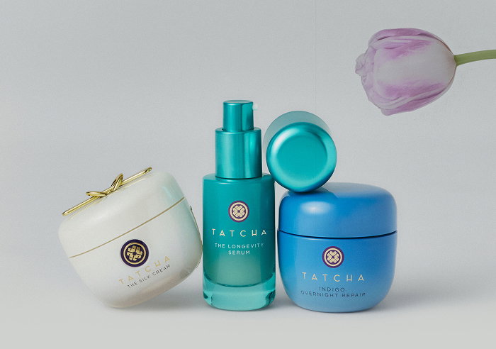 A selection of Tatcha skincare formulas with a flower in the background.