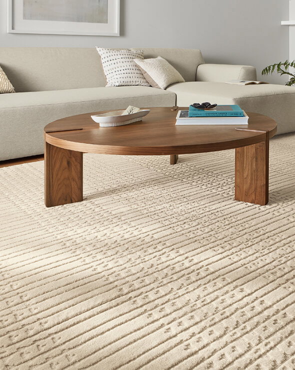 Bria rug with cream textured pattern beneath a walnut coffee table and beige sectional.