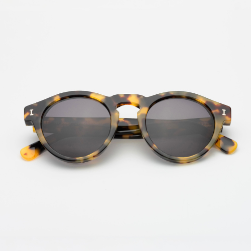 A studio product shot of the Leonard sunglasses in a rich, honey-colored tortoise shell acetate. The frames feature a classic round silhouette with a keyhole bridge and the signature silver 