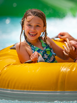 A girl smiling riding Mammoth Falls in a raft 