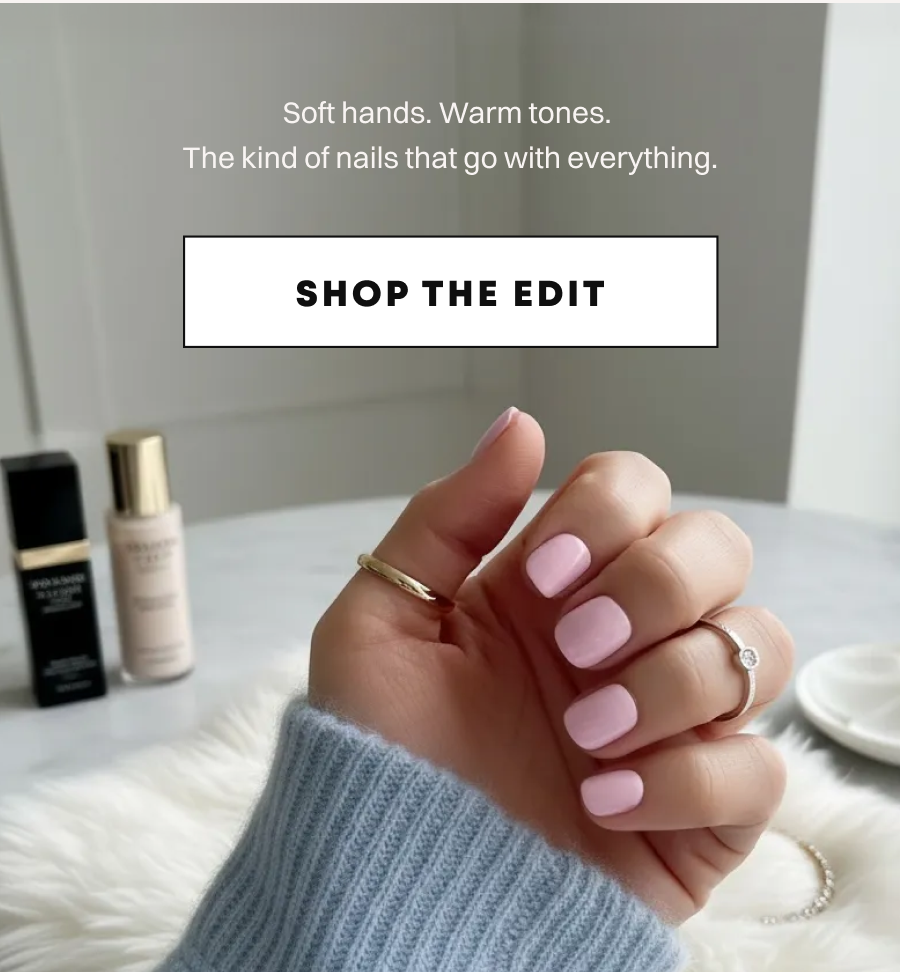 Hand in light blue sweater showing soft pink press-on nails while holding skincare products