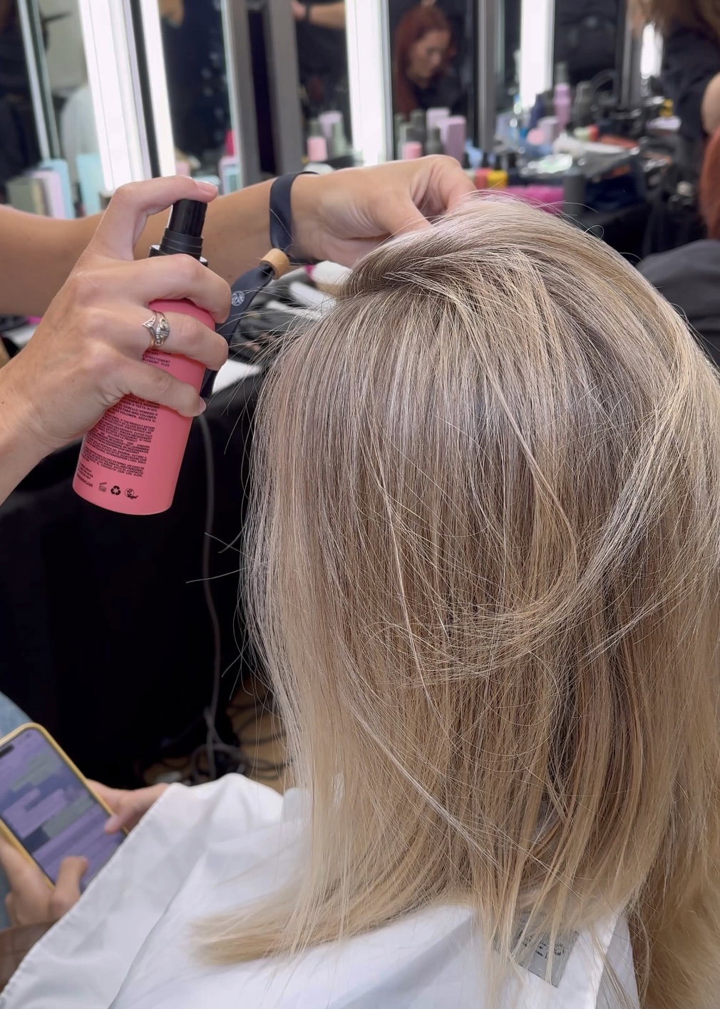 A person sprays a product onto another person's wet hair.