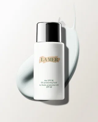 Bottle of The SPF 50 UV Protecting Fluid with cream smear in the background.