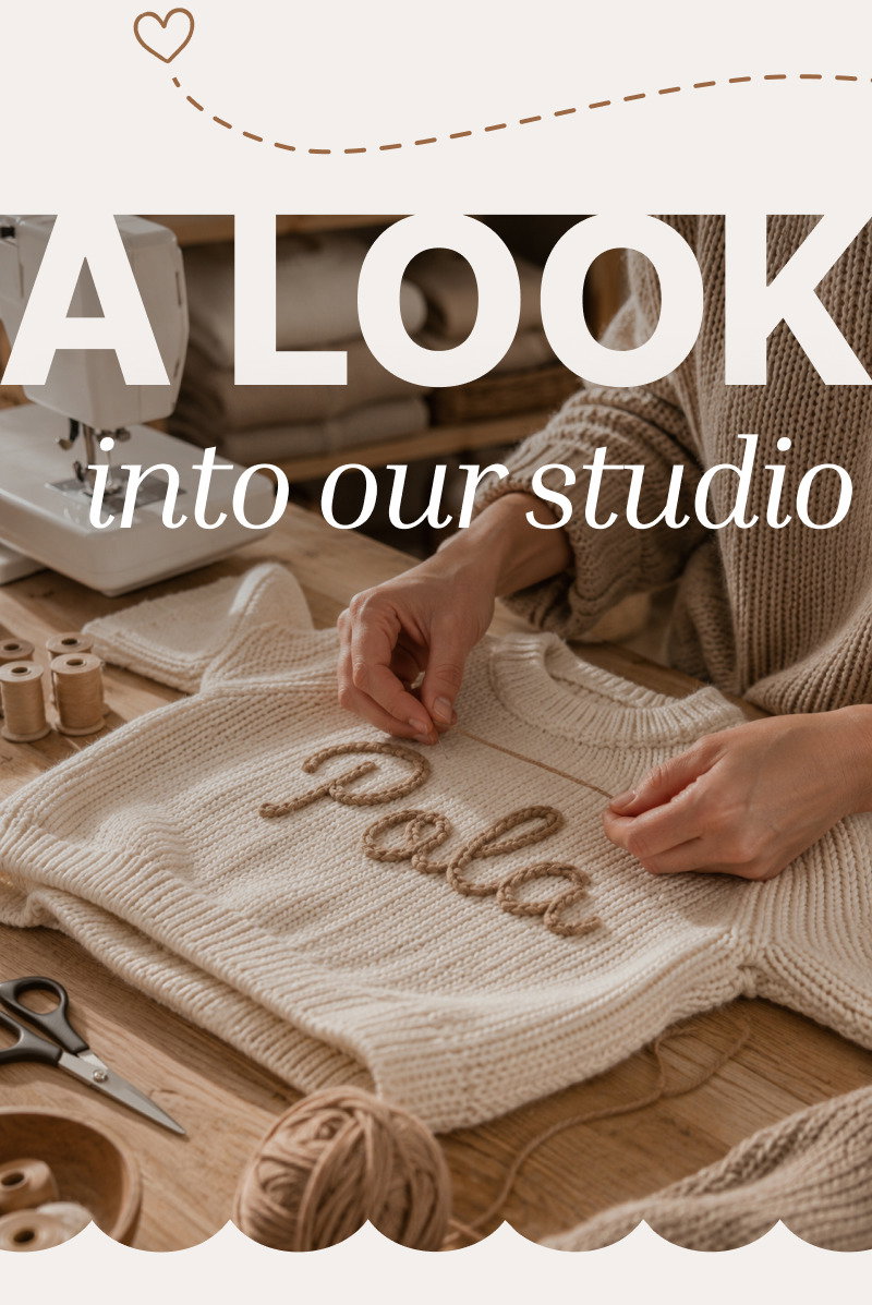 Hands placing a personalized knit blanket on a studio table with yarn, wooden toys, and handmade details around it.