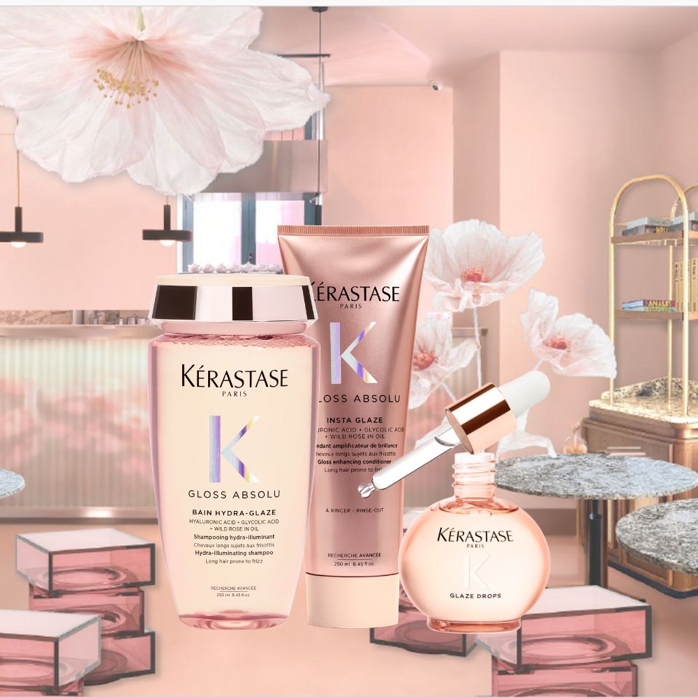 Tre prodotti Kérastase Gloss Absolu  shampoo, balsamo e siero Glaze Drops  su sfondo rosa con fiori