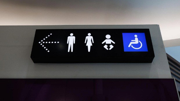 A sign for toilet facilities shows icons of an arrow left, a man, a woman, a baby and a wheelchair user.